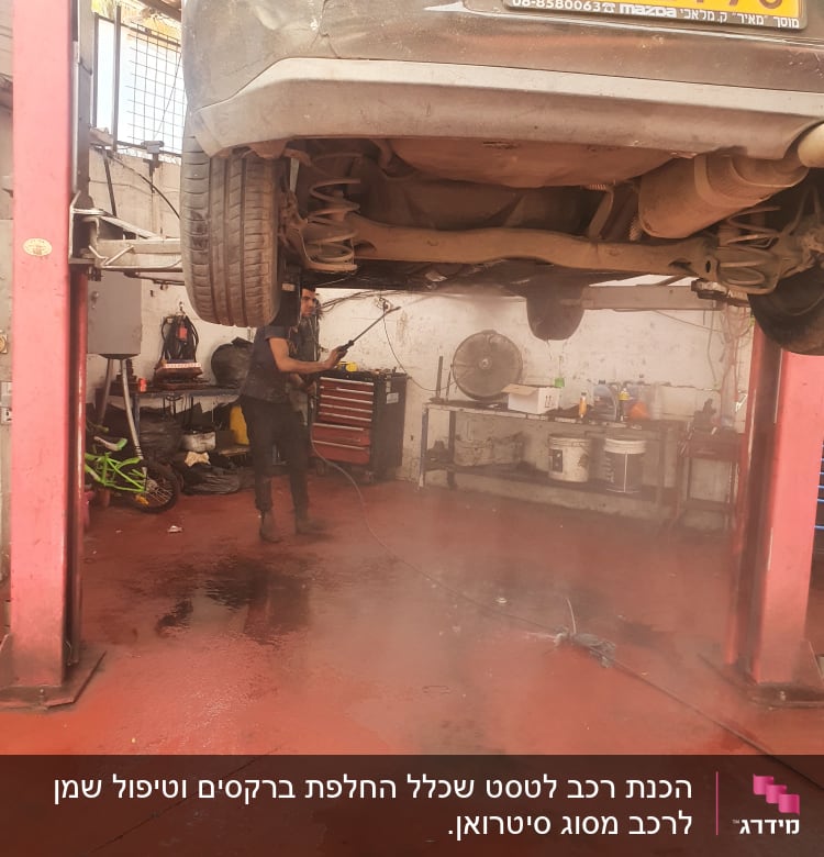 רכב מורם במוסך, עובד עם מכונת שטיפה